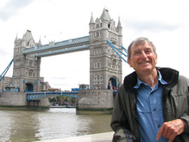 photo of author standing beside the Thames River in London with the Tower Bridge in the background